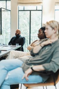 Focused individuals during a business meeting in an office with large windows.